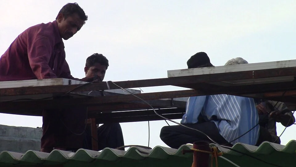 Workers installing solar panels on a roof in India